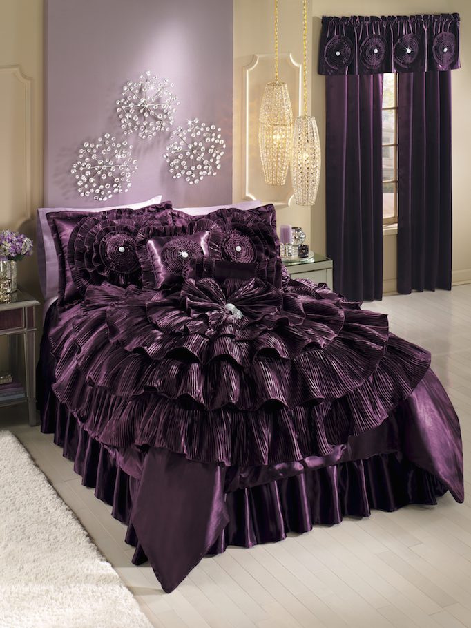 A plum bed set of extravagant ruffles sewn into a huge flower shape, with matching ruffled shams, curtain and throw pillows.