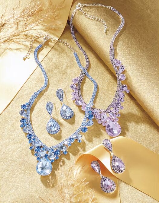 Two elegant necklaces with blue and purple gemstones, accompanied by matching earrings, on a golden background.