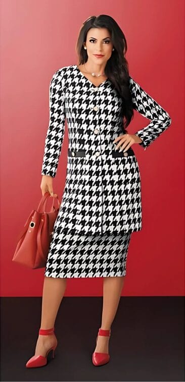 Woman in a black and white houndstooth dress with a matching jacket, red heels, and a red handbag against a red background.