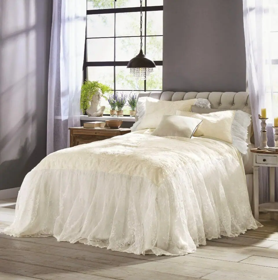 Romantic sheer white lace bedspread and matching shams, with lavender and a Grecian lady planter on a sunny window ledge.