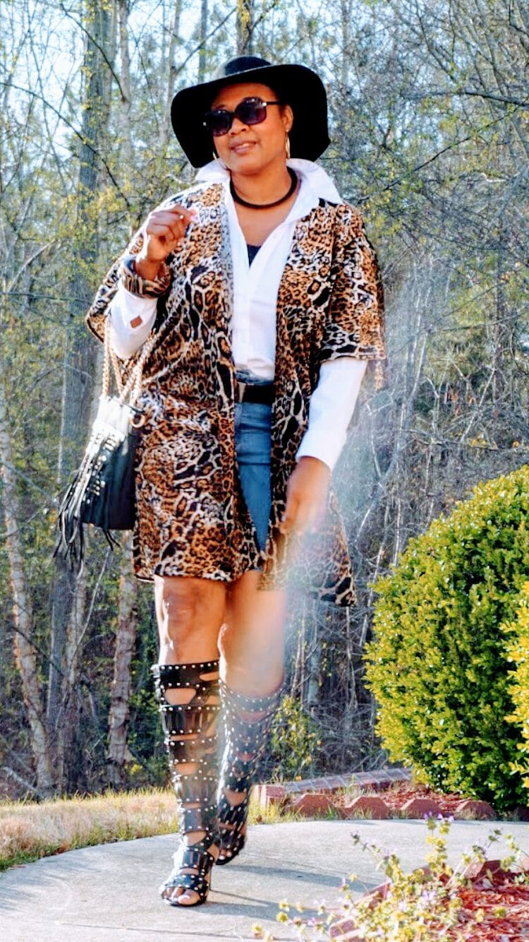 A Midnight Velvet customer in sunglasses, a shirt and animal print cardigan, black studded boots and bag, and a black hat.