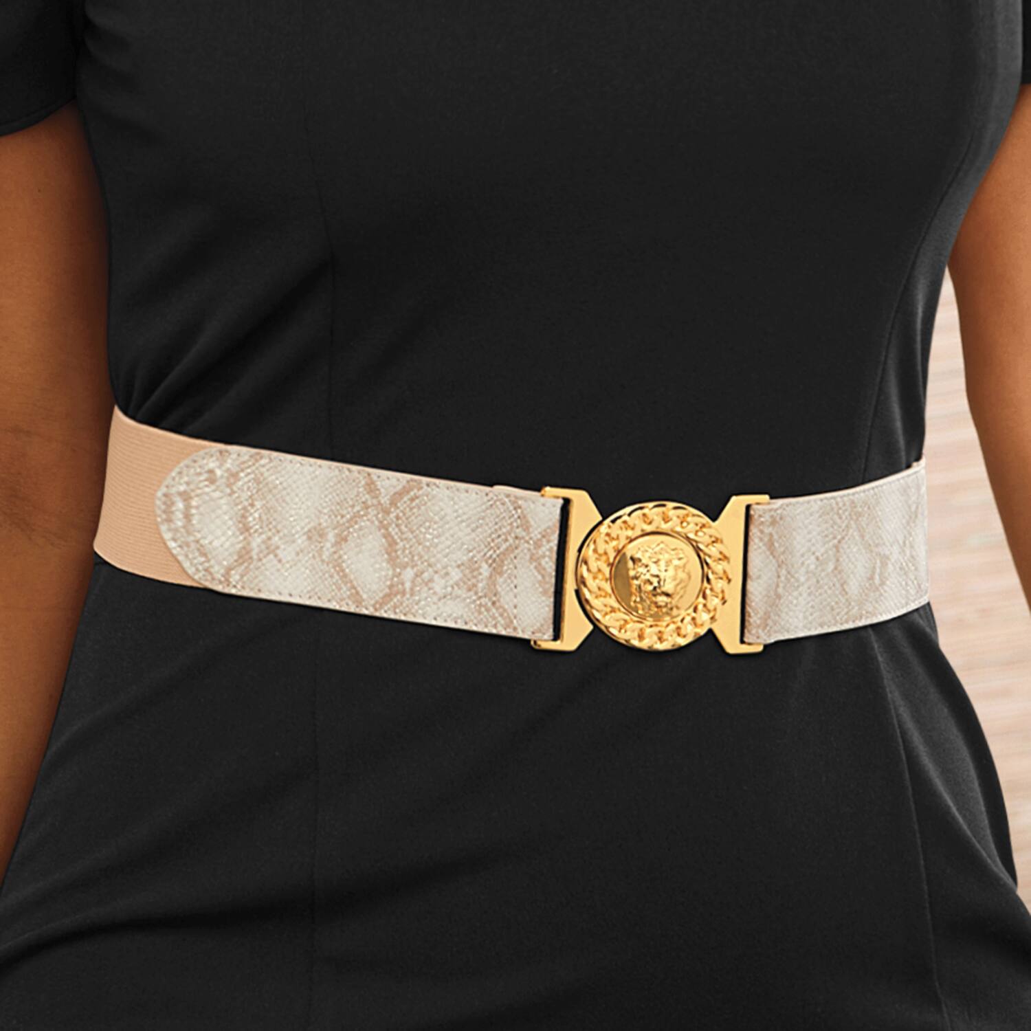 A stylish belt with a snake print design and a gold lion head buckle, worn over a black top.