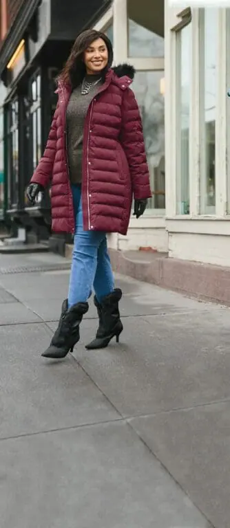 Plus-sized model wearing a burgundy parka with black fur boots.