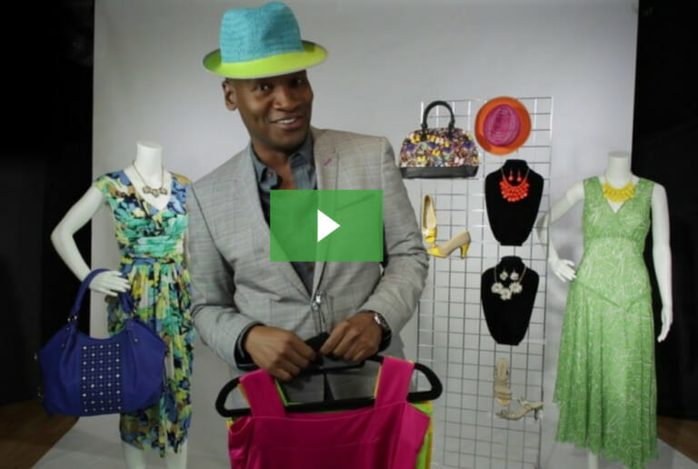 A video of a black man in a suit and a blue and lime hat, surrounded by women's accessories and fashions on mannequins.