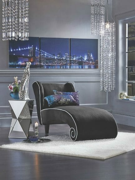 Modern black chaise, mirrored side table, tryptic cityscape wall art, crystal hanging beads, and a white plush throw rug.
