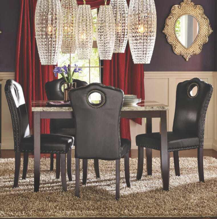 Faux marble top table with four black faux leather studded chairs, red drapes, gold framed mirror, and six crystal lights.