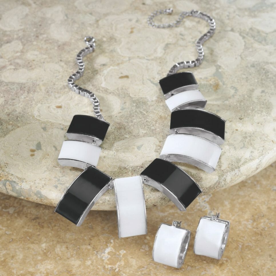A silver square chain necklace with black and white rectangle bars and matching white earrings.