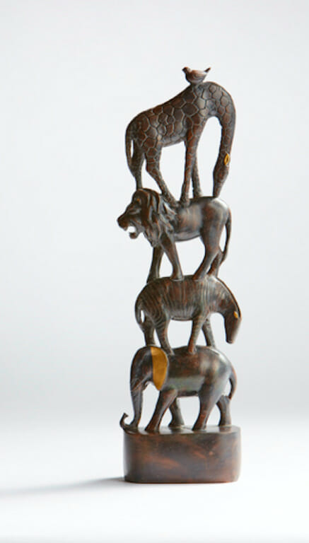 A wood-like figurine of stacked African animals: an elephant, zebra, lion, giraffe and bird.
