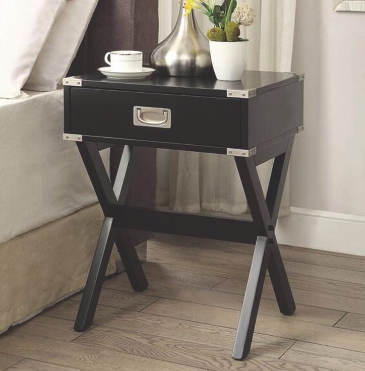 A black wooden side table with a drawer and silver corner guards, in the style of a folding luggage rack.