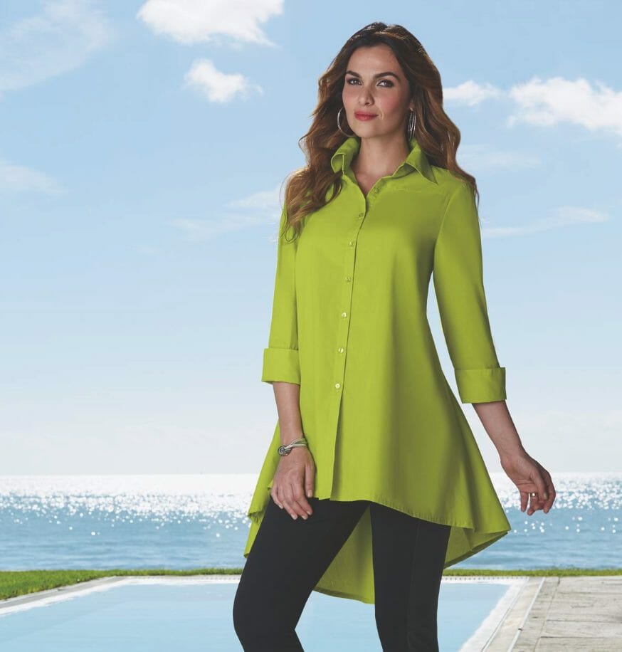 A long-haired woman poolside in a lime green shirt buttoned, high-low tunic and black leggings.