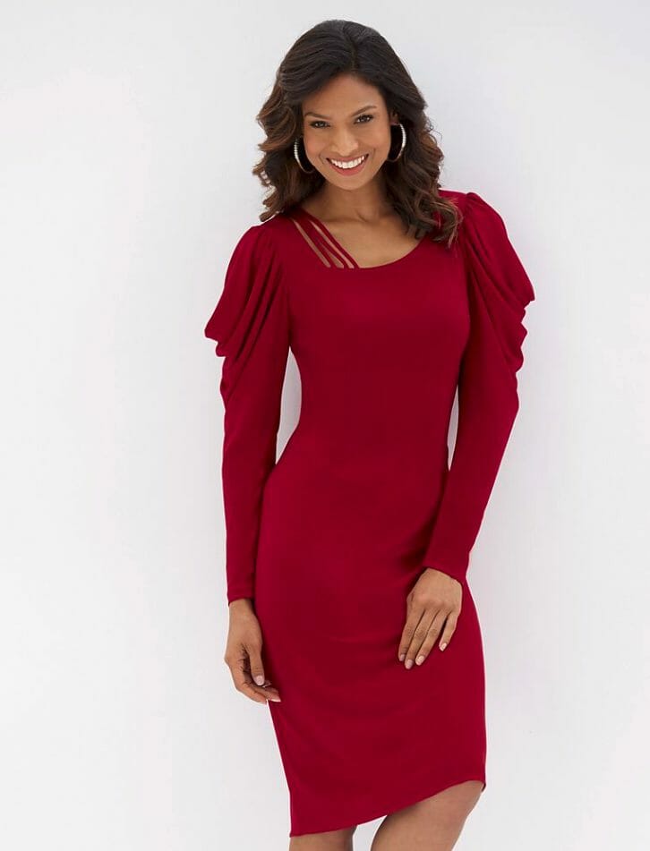 A smiling Hispanic woman wearing a fitted long-sleeve red dress with folds of fabric at the shoulder and sleeve top.