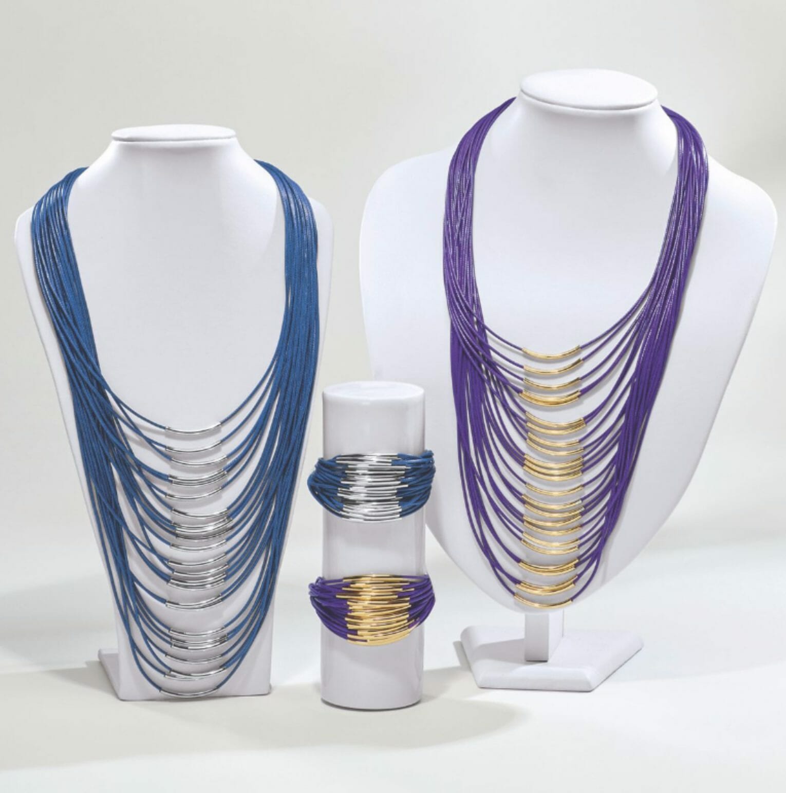 Two multi-strand necklaces and matching bracelets, one in blue and silver, the other in purple and gold.