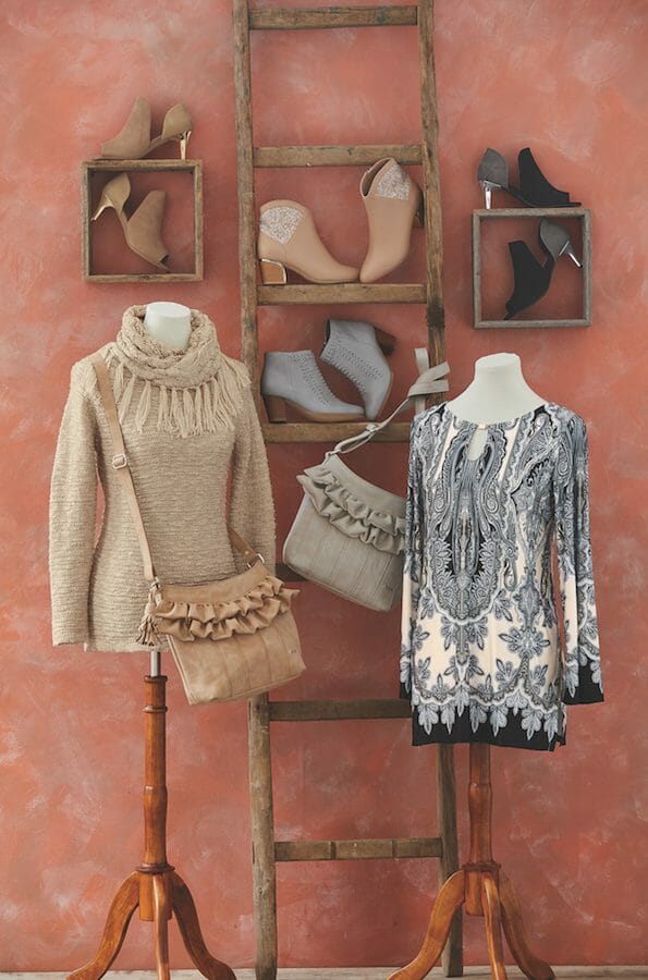Two mannequins, one in a sweater, one in a gray print top, gray and tan ruffled bags, gray, tan, beige, and black booties.