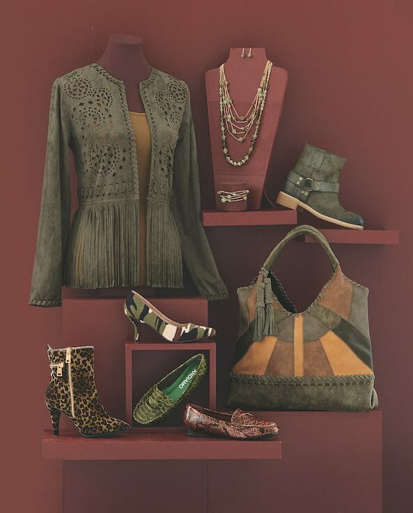 A moss green fringed and cutout jacket over a mustard top, a beaded necklace set, a patchwork bag, and five shoes and boots.