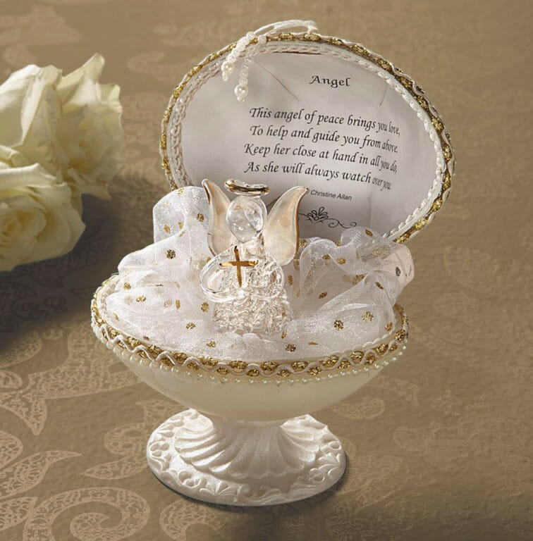 A white and gold figurine of a small glass angel in an open egg on a pedestal, with a printed Angel inscription.