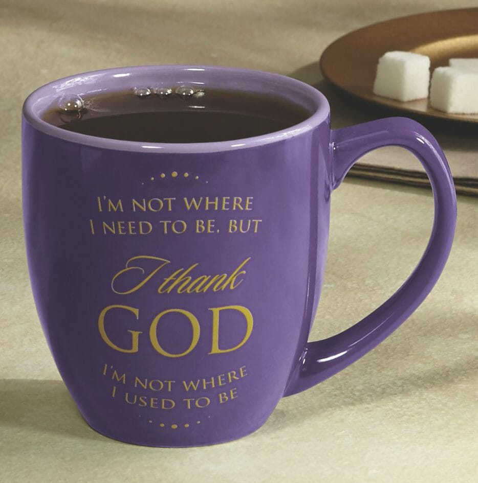 A purple coffee mug, inscribed in gold, I'm not where I need to be, but I thank GOD I'm not where I used to be.