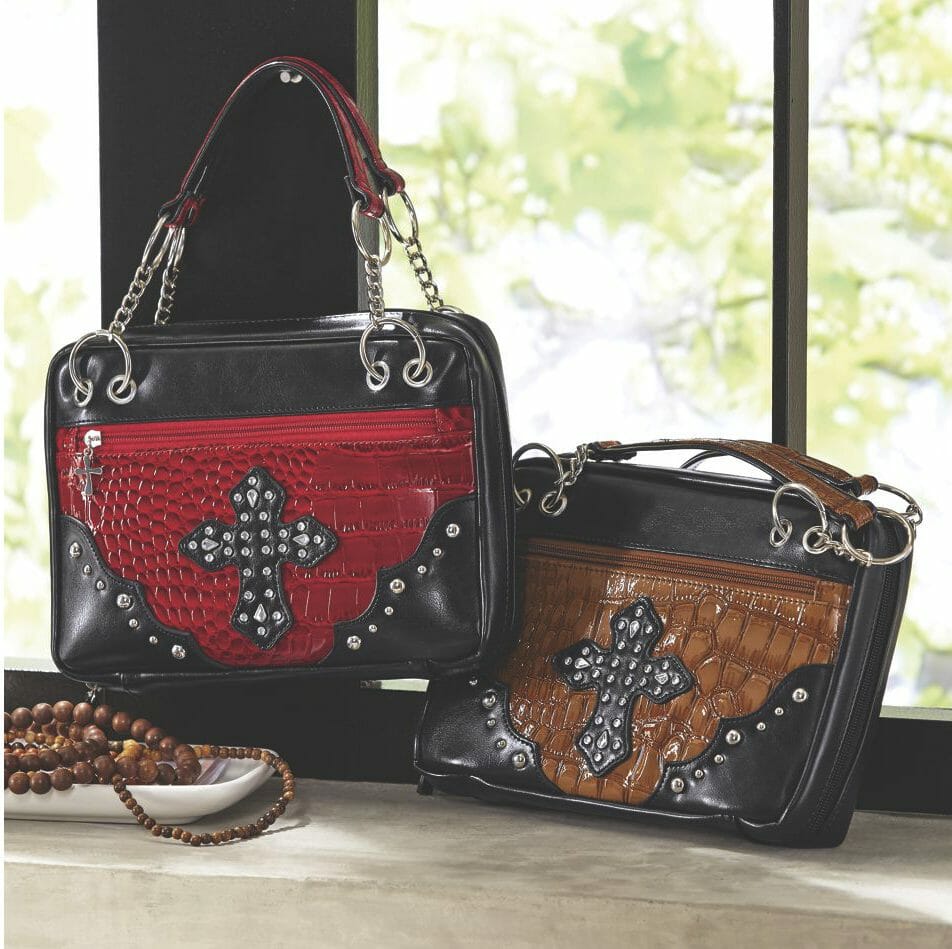 Two black faux leather bags with zippers and a studded cross on a faux reptile insert, one in red and one in brown. 