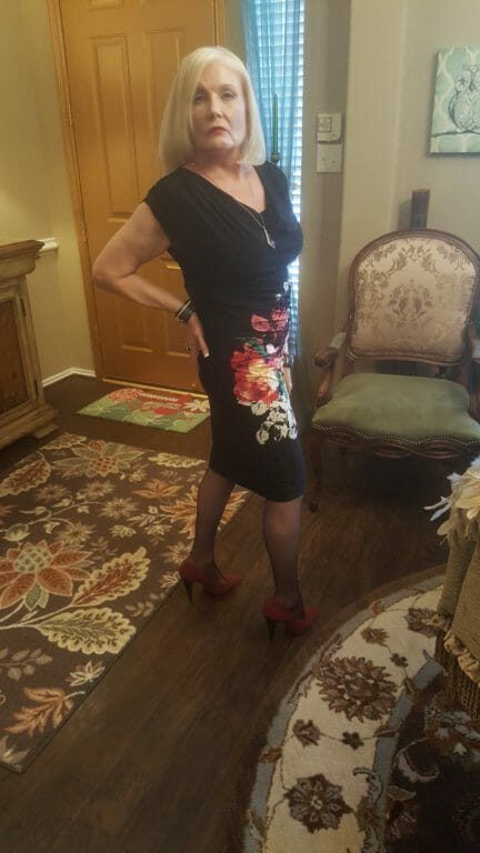 Side view of a Midnight Velvet customer in a black V-neck dress with a diagonal splash of white, red and yellow flowers.