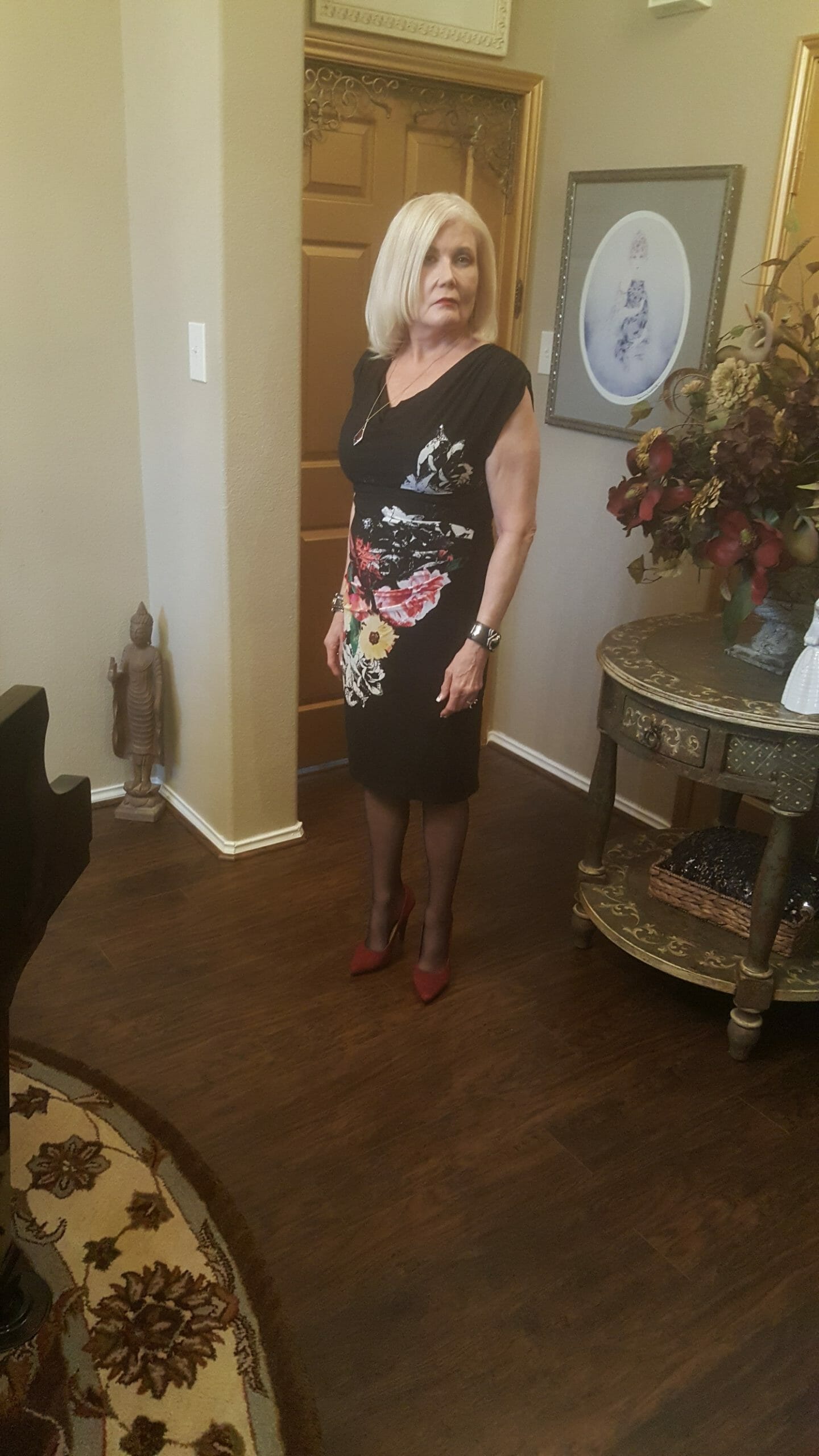 Side view of a Midnight Velvet customer in a black V-neck dress with a diagonal splash of white, red and yellow flowers.