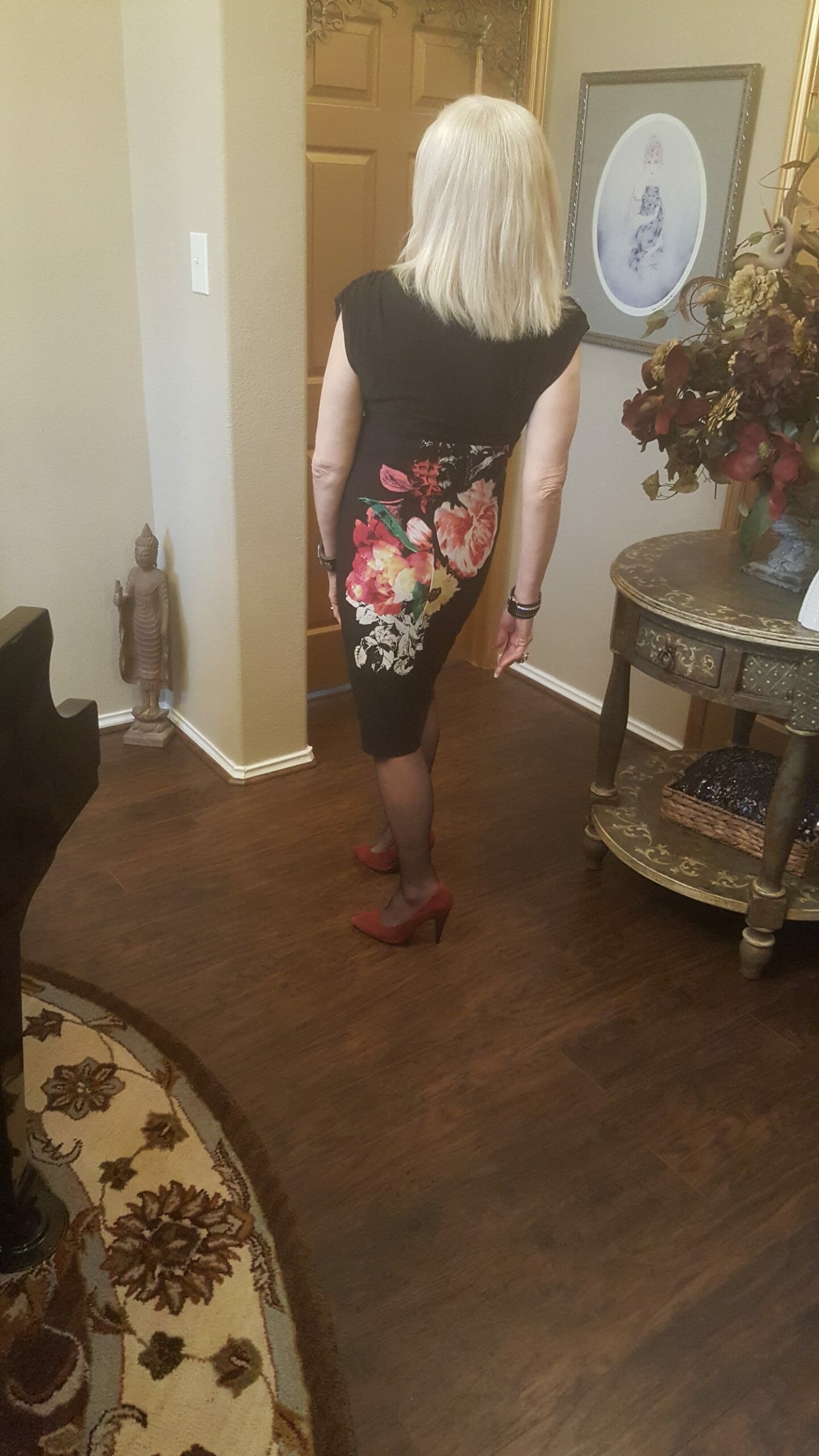 Back view of a Midnight Velvet customer in a black V-neck dress with a diagonal splash of white, red and yellow flowers.