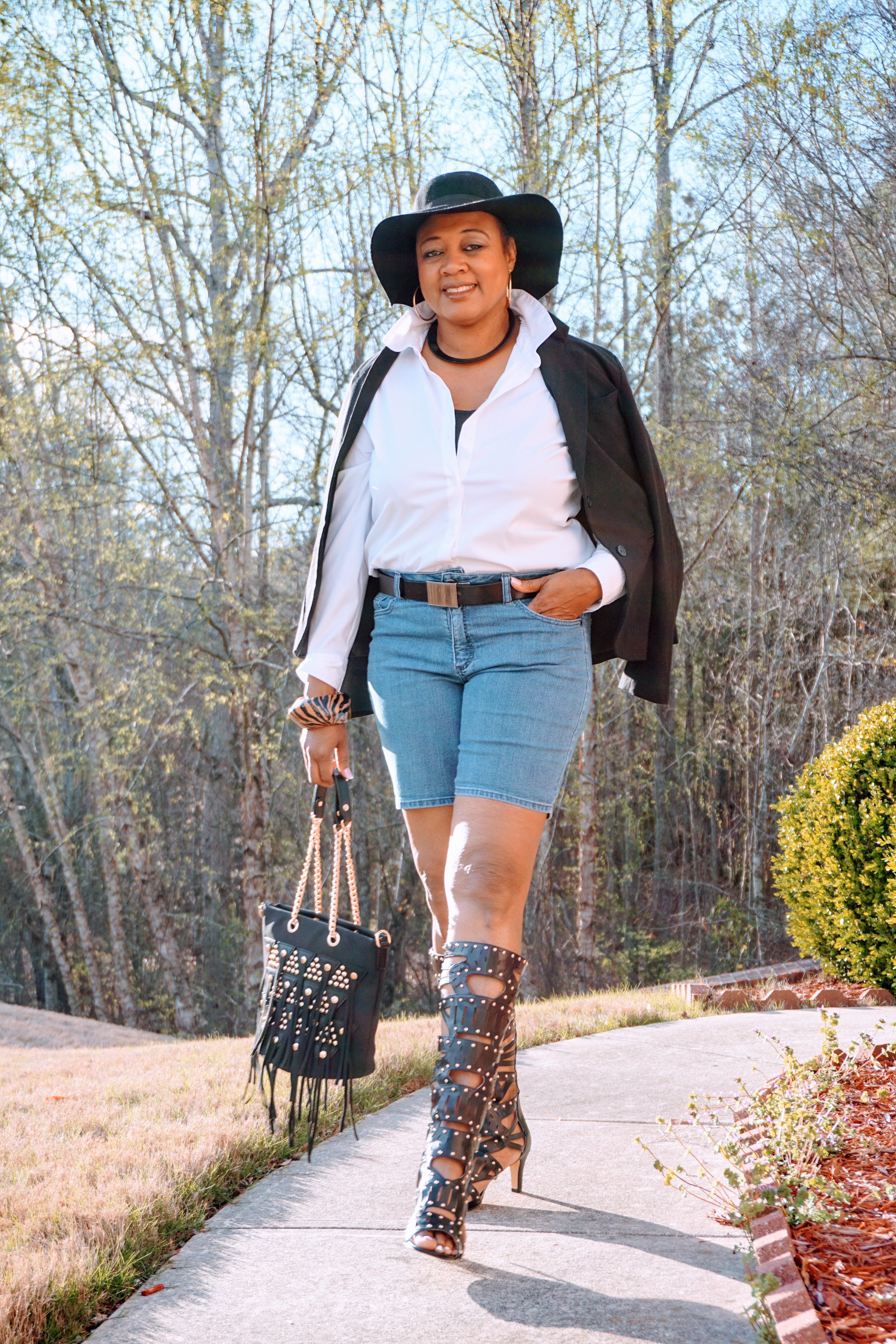A Midnight Velvet customer in a white shirt, black jacket, jean shorts, black studded boots, and a wide brimmed black hat.