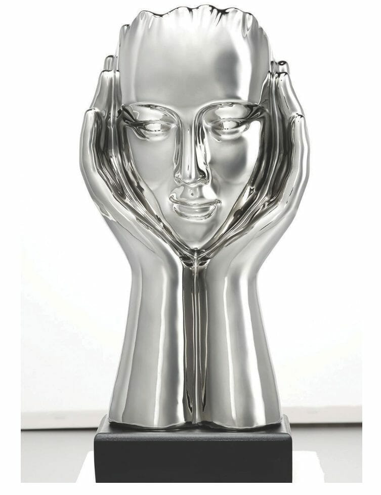 A silver figurine of a contemplating head supported by hands on each side, mounted on a black base.