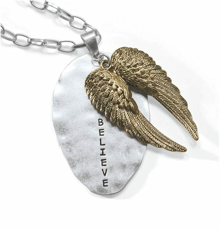 A silver necklace with a silver oval pendant engraved with BELIEVE, and attached gold angel wings.