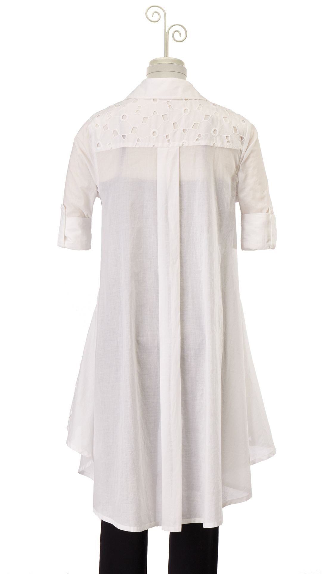 Back view of a mannequin displaying a white cutwork button-shirt tunic with an asymmetrical hem.