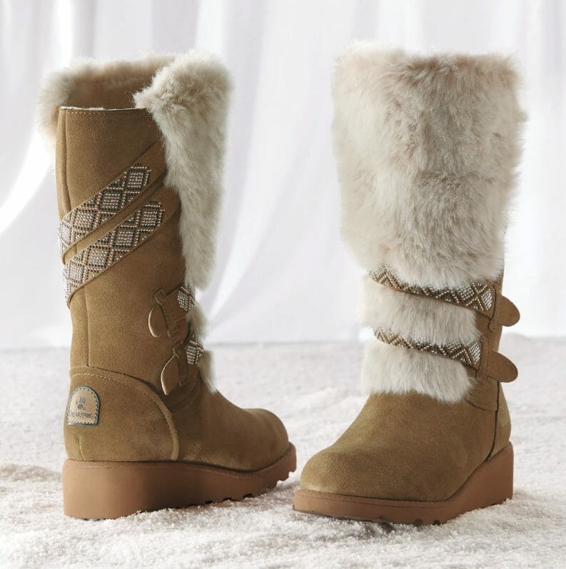 Tall, tan faux suede boot with ivory faux fur on the front, with two Southwest-look straps wrapped around to the front.