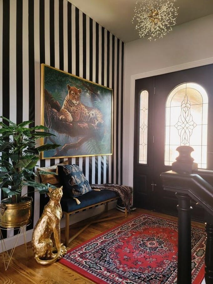 Golden Leopard Statue sitting in entryway of a home, in front of black and white striped wall on a red rug